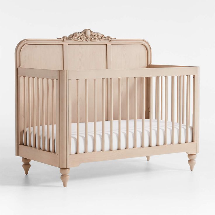 a wooden crib with white bedding and pillows on the bottom row, in front of a white background