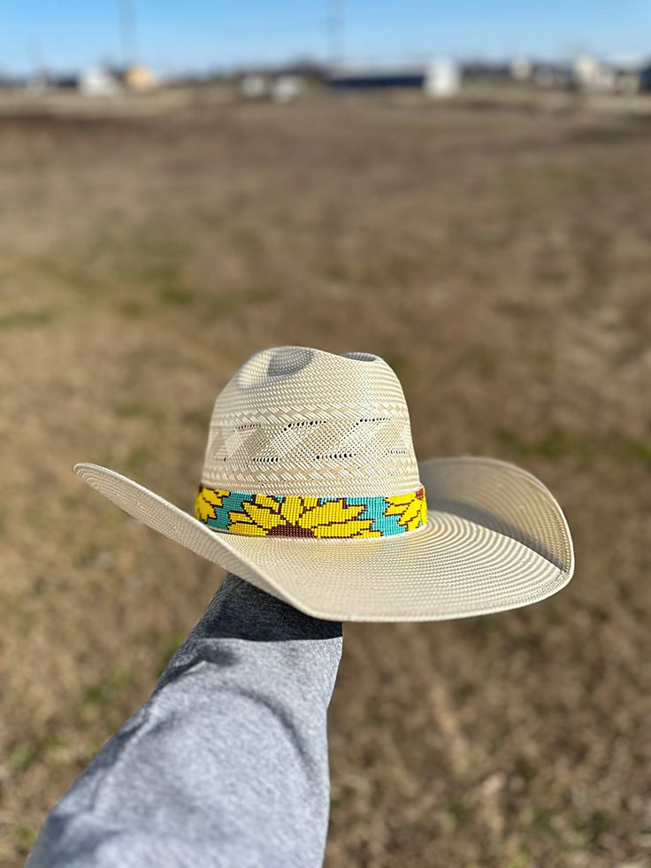 Add a touch of nature to your hat with our Sunflower Hatband. Handcrafted with intricate sunflower beads, this hat band is the perfect accessory for any outdoor excursion. The black leather ends add an extra 11 1/2 inches, providing a comfortable and secure fit. The whole hat band measures 30 1/2 inches, making it versatile for all hat sizes. Adjustable Country Style Hat Bands For Beach, Country Style Adjustable Hat Band For Beach, Country Style Hat Bands For Outdoor, Adjustable Artisan Sun Hat For Spring, Western Style Beach Hat Bands With Adjustable Fit, Adjustable Hat Bands For Outdoor, Bohemian Fitted Hat Bands For Vacation, Adjustable Western Sun Hat For Outdoor, Adjustable Hat Bands For Kentucky Derby