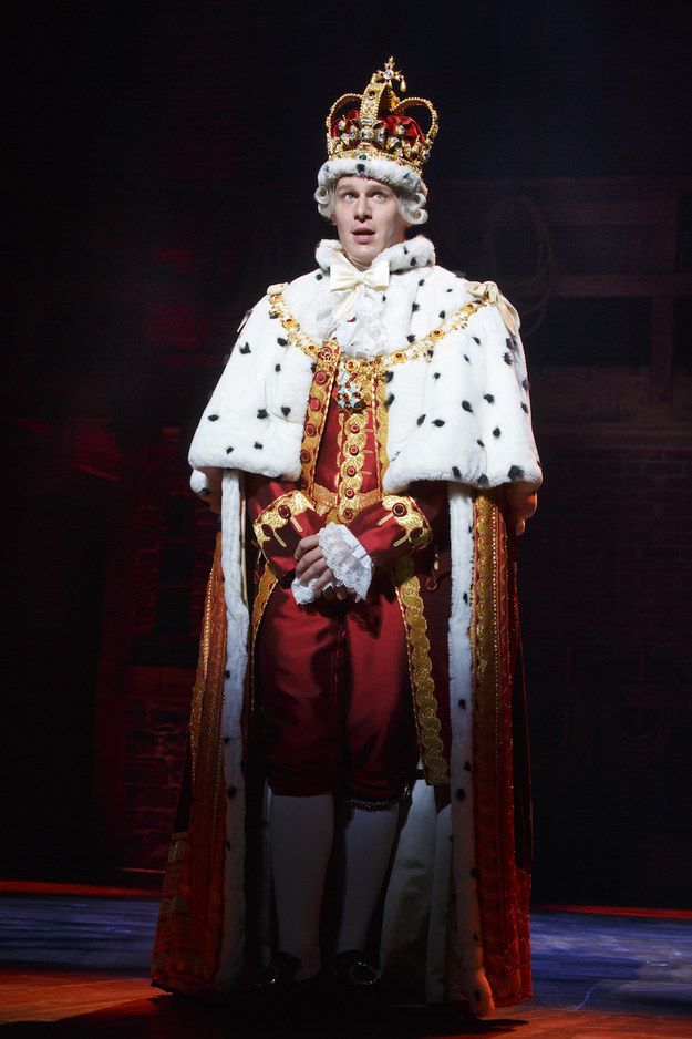 a man in a white and red outfit with a crown on his head is standing