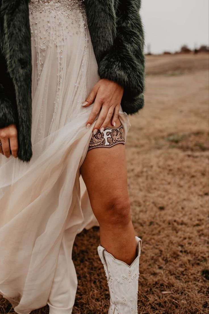 a woman in white boots and a dress is holding her leg up to the ground