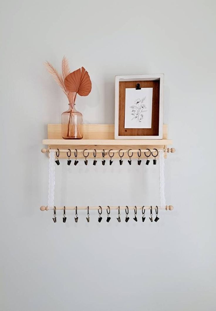 a wooden shelf with hooks on it next to a framed photograph and a small potted plant