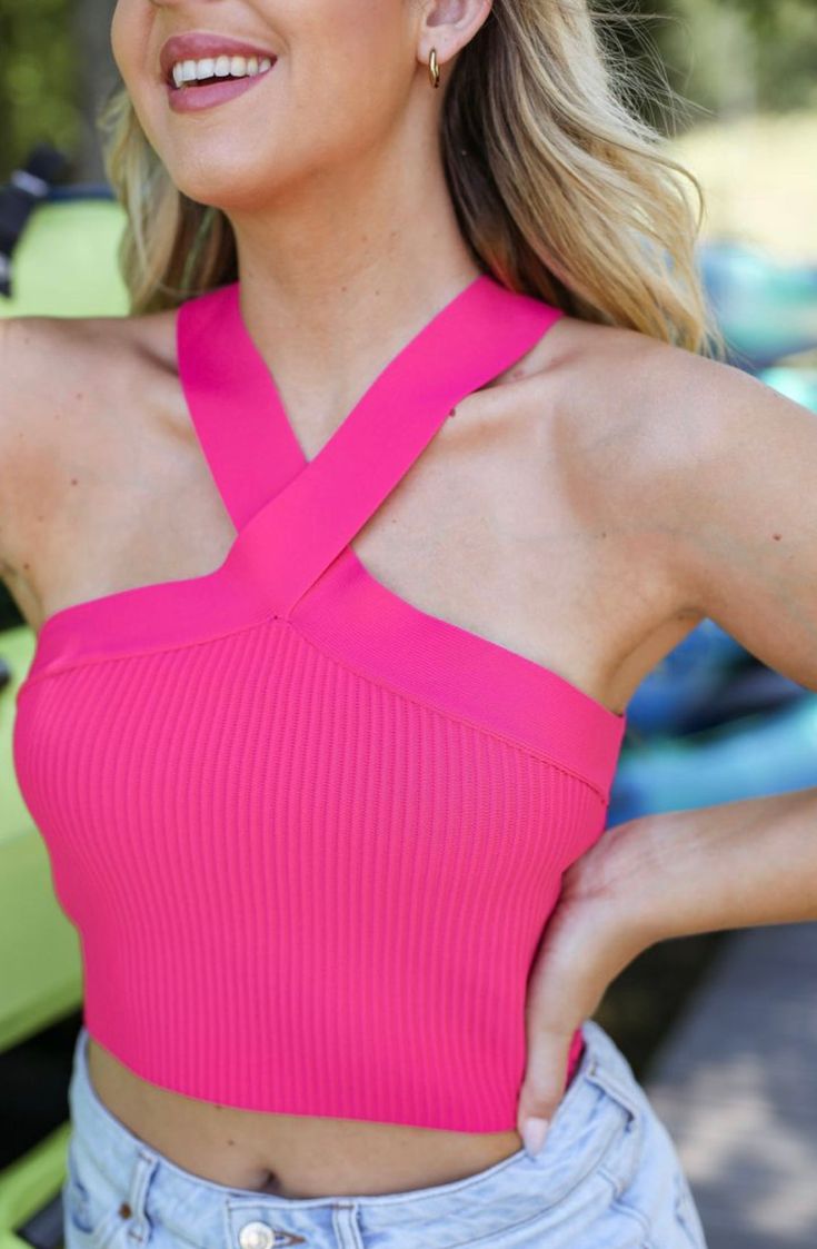 a woman with blonde hair wearing a pink top and denim shorts, posing for the camera