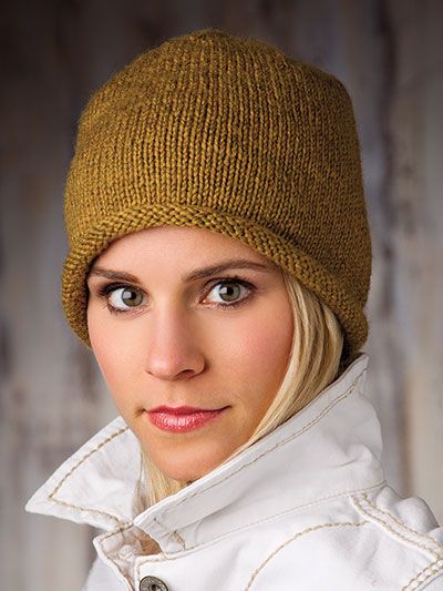 a woman with blonde hair wearing a brown knitted beanie hat and looking at the camera