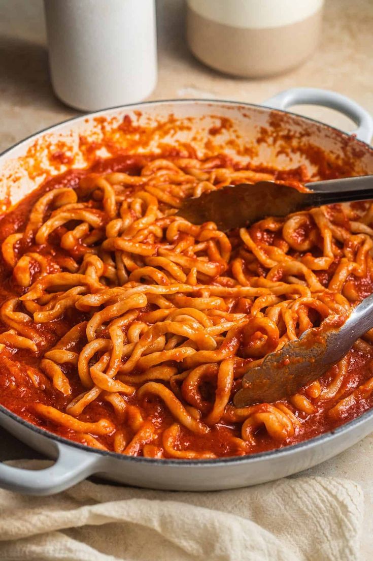 a pan filled with spaghetti and sauce on top of a table