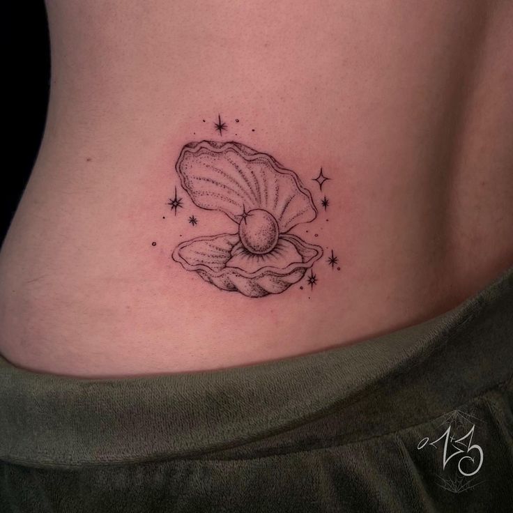 a woman's stomach with a shell tattoo on her belly and stars in the background