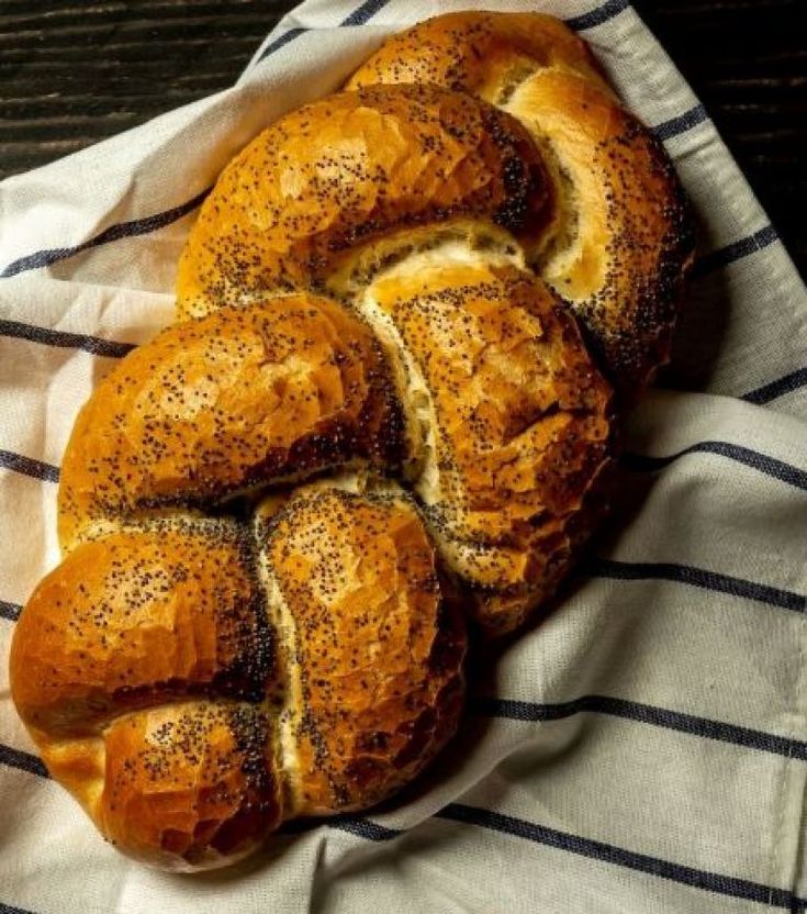 a loaf of bread with poppy seed sprinkles on a striped towel next to a cup of coffee