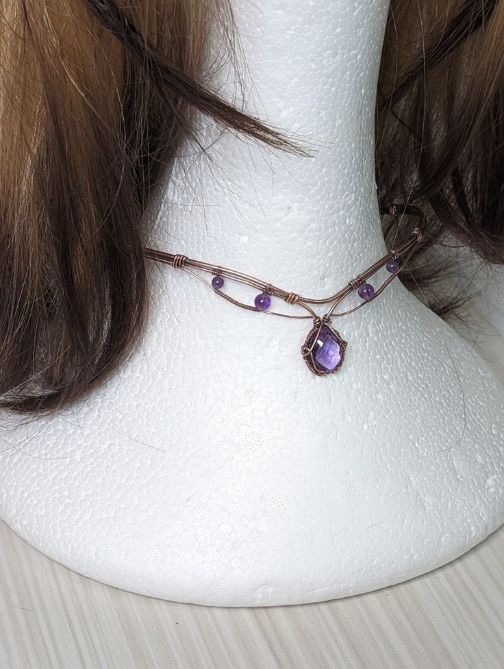 Enhance your look with this stunning 6ct Amethyst choker in copper! Handcrafted with quality materials, this choker features a beautiful Amethyst gemstone in the center, set in copper wire wrap that creates a beautiful and eye-catching design. The copper wire wrap is intricately detailed and flows gracefully around the gemstone, giving it an elegant feel. The choker fits comfortably around the neck and is lightweight enough to be worn all day. You'll be sure to make a bold statement with this un Copper Wire Wrapped Necklace, Adjustable Hand Wrapped Amethyst Necklace, Handmade Adjustable Crystal Necklaces With Copper Wire, Hand Forged Adjustable Purple Jewelry, Adjustable Hand Forged Purple Jewelry, Handmade Adjustable Crystal Necklace With Copper Wire, Adjustable Wire Wrapped Choker As Gift, Adjustable Hand Wrapped Copper Crystal Necklaces, Adjustable Copper Crystal Necklace With Natural Stones