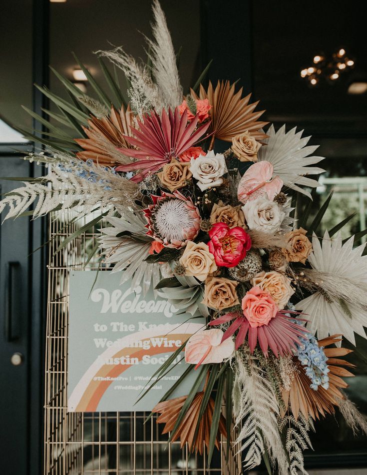 an arrangement of flowers on display in front of a sign that reads welcome to the wedding