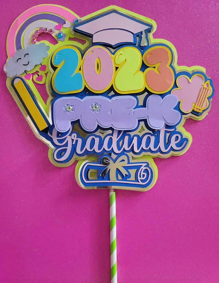 a cake topper with the words graduate and graduation written in blue, yellow, and pink