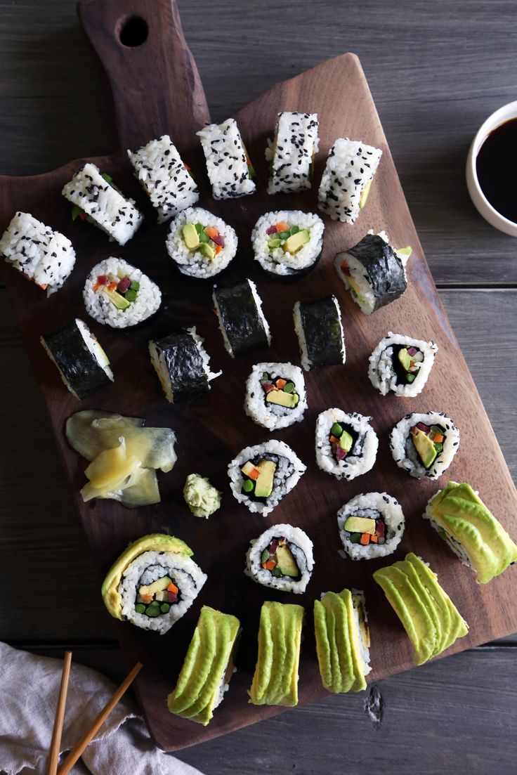 sushi on a wooden cutting board with chopsticks and a cup of coffee