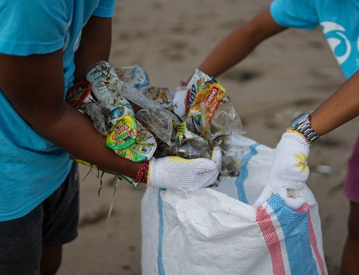 two people holding bags full of food on the beach