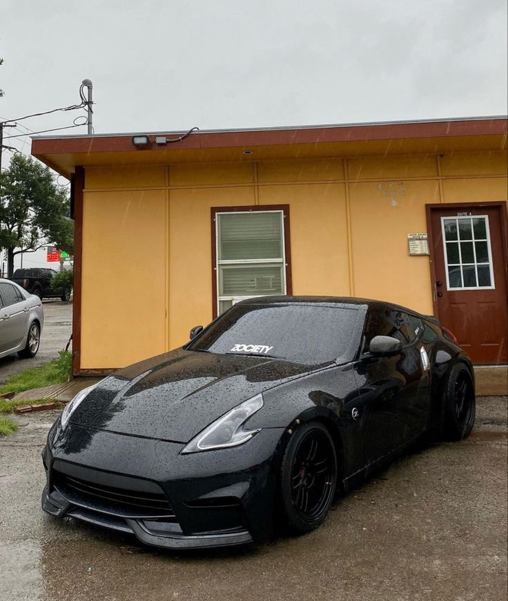 a black sports car parked in front of a yellow building