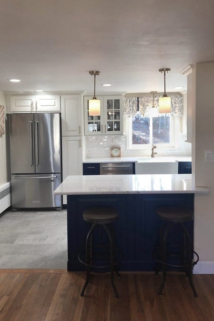 a kitchen with two stools and an island in the middle, next to a refrigerator