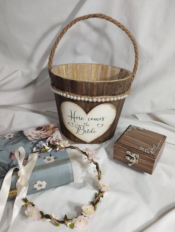 a wooden basket with a heart on it next to a wedding ring box and other items