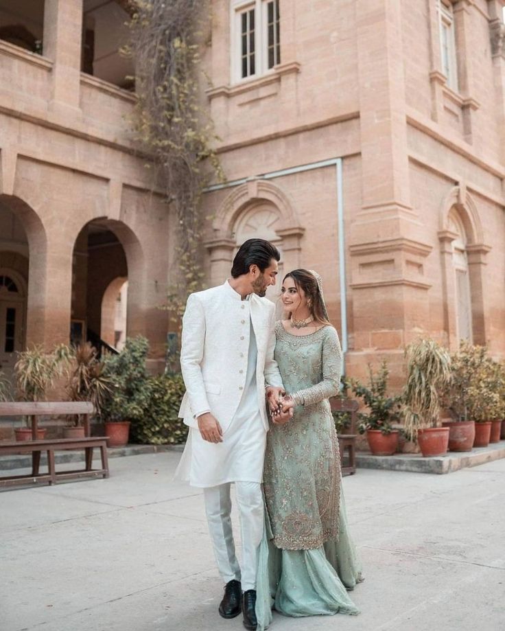 a man and woman standing next to each other in front of a building