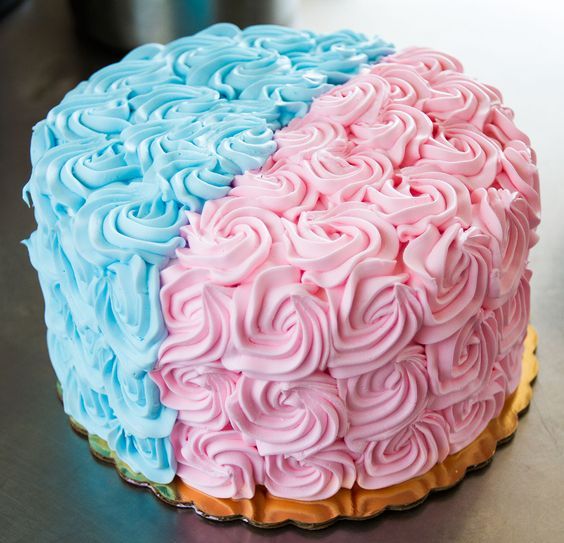 a cake with pink, blue and yellow frosting on it's side sitting on a table