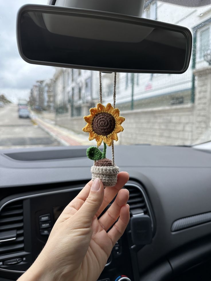 a person is holding a sunflower decoration in their hand as they drive down the road