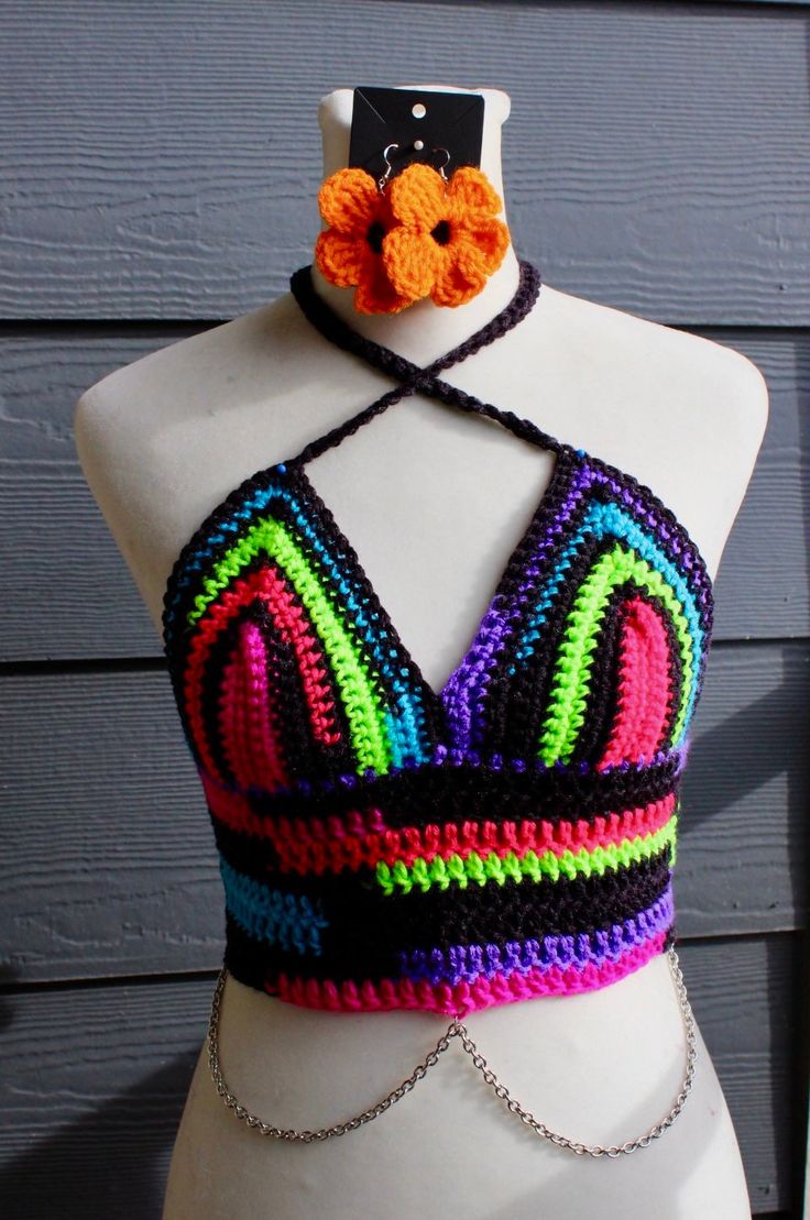 This top has a halter tie top as well as an adjustable corset back to allow for different sizes or waists and rib cages to still be accommodated. It is made out of a neon colors and black variegated yarn and the chains are made with nickel free metal. Earrings pictured sold separately Fitted Strappy Halter Top For Festivals, Black Bohemian Halter Top For Party, Multicolor Triangle Halter Top For Party, Multicolor Halter Neck Crop Top For Party, Fitted Multicolor Halter Neck Crop Top, Multicolor Triangle Halter Top For Festival, Multicolor Halter Neck Crop Top For Festival, Black Triangle Halter Top For Festival, Multicolor Halter Neck Crop Top