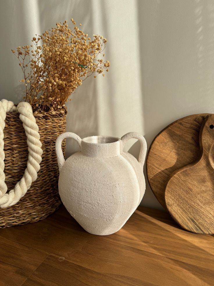 three ceramic vases sitting next to each other on a wooden table with rope handles