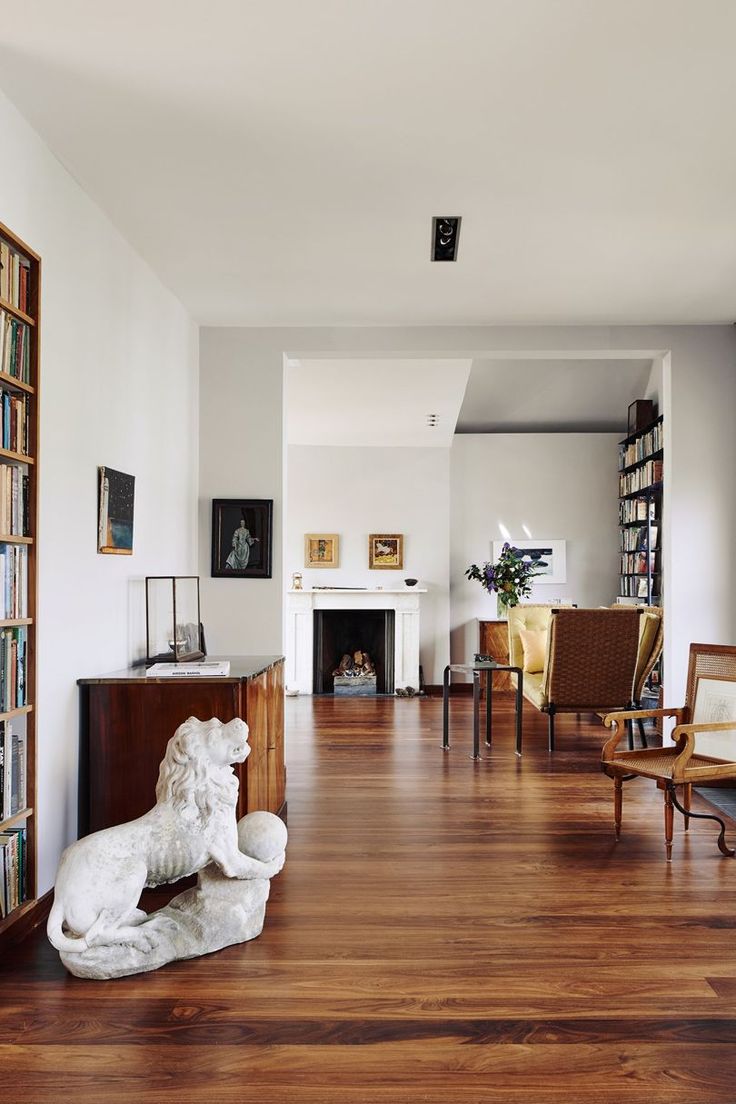 a living room filled with furniture and bookshelves on top of hard wood floors