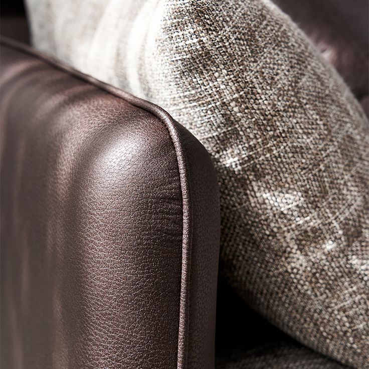 a close up view of the back end of a leather couch with two pillows on it