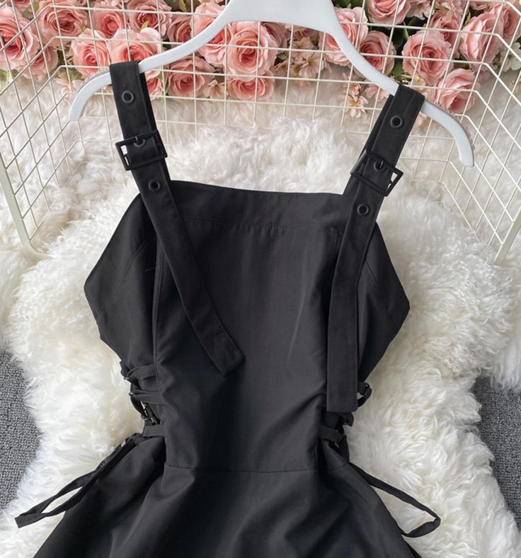 a black dress hanging on a rack with roses in the background