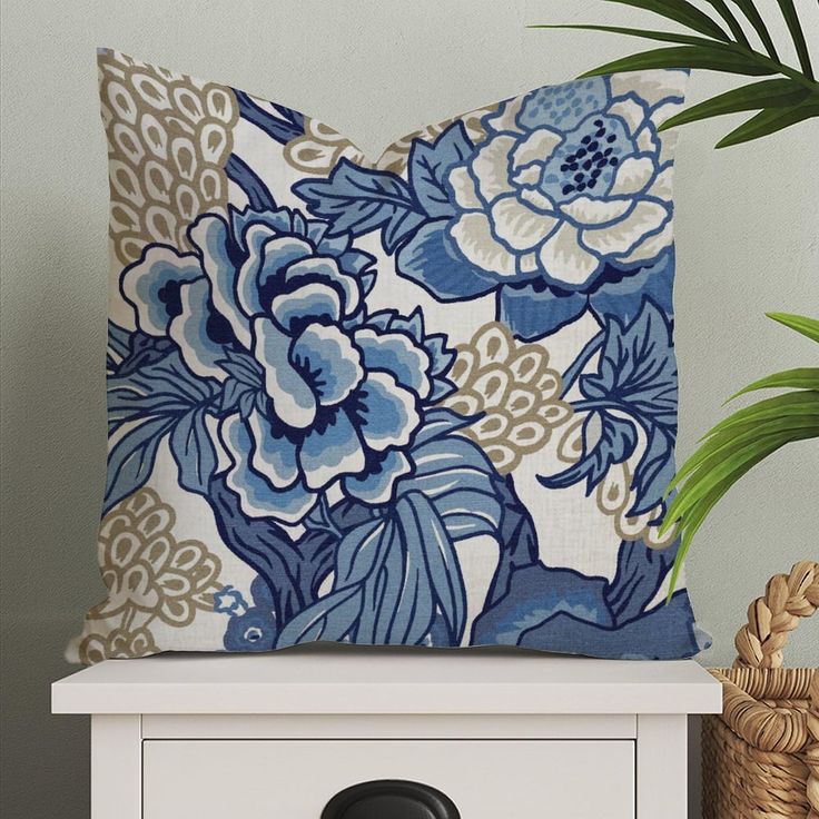 a blue and white pillow sitting on top of a table next to a potted plant