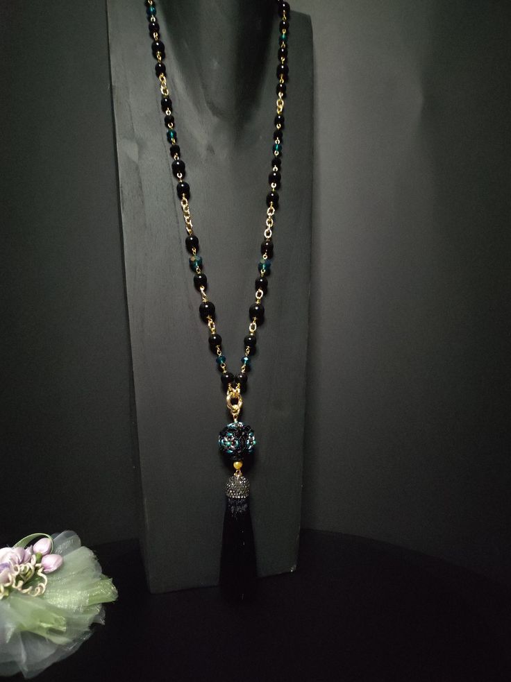 Beautiful sautoir necklace with long tassel. The main elements of this necklace are two: a large 30 mm pearl covered in beads and crystals and a splendid black tassel with Marcasite. These crystals give a lot of brightness and make the necklace very elegant. The pearl is covered by hand with different types of beads, a precision and difficult job to perform. The necklace is made with black agate beads of different sizes and crystals. Some points are highlighted with the beautiful emerald green color which gives a mystical look to the necklace. Everything matches perfectly, colors and shapes. The closure is an 18K gold-plated opening ring. The pendant with the ball and the tassel can be removed if desired and you can only wear the simple necklace. The necklace is very elegant, perfect for l Elegant Long Necklace With Large Beads, Elegant Necklace With 108 Beads For Gift, Elegant Necklace With 108 Beads Pendant, Elegant Black Tassel Necklace, Elegant Handmade Black Long Necklace, Elegant Black Long Necklace For Gift, Elegant Jewelry With Tassels And Round Beads, Elegant Round Beaded Tassel Jewelry, Elegant Necklace With 108 Beads For Party