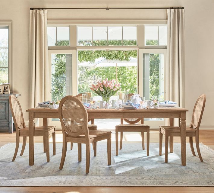 a dining room table and chairs in front of a large window with an area rug on the floor