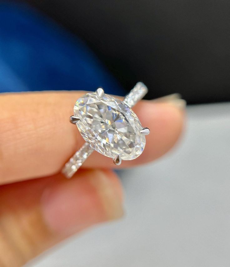 a close up of a person's hand holding a ring with a diamond on it