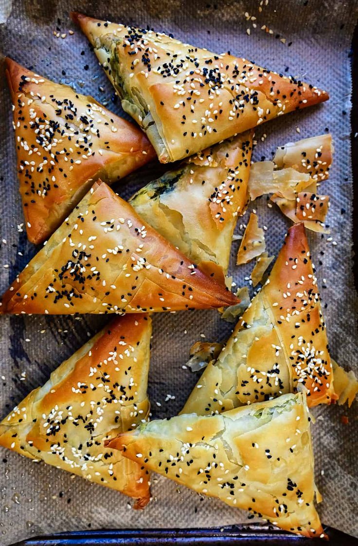 several pastries on a baking sheet with sesame seeds and seasoning sprinkles