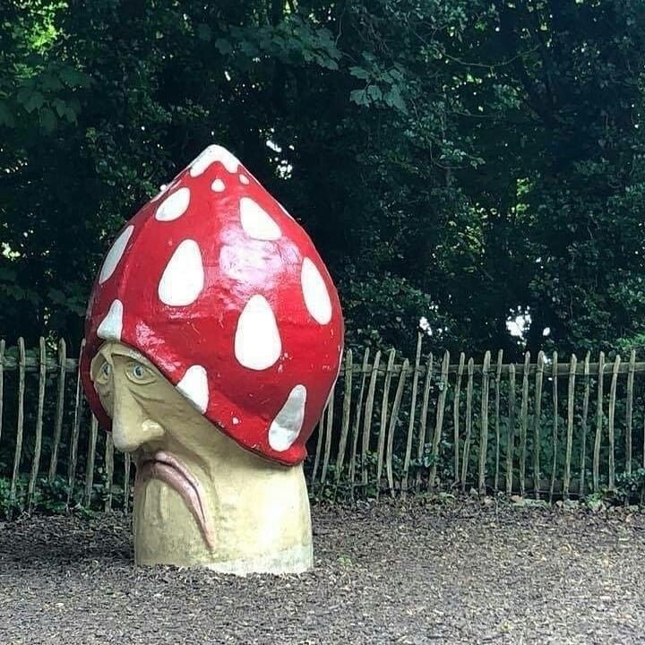 a mushroom shaped sculpture in front of a fence