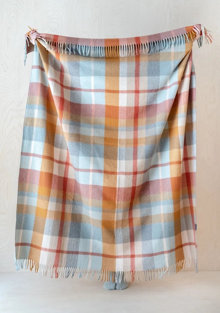 an orange and blue plaid blanket hanging on a wall