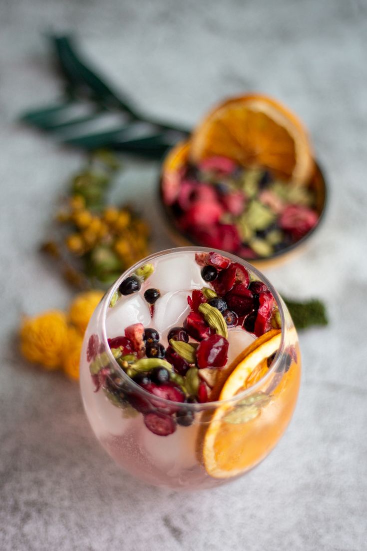 A short round glass of gin and tonic, also filled with ice, with garnishes, on a concrete looking ground and with blurry garnishes on the background. Dried Citrus Cocktail Garnish, Gin And Tonic Garnish, Dehydrated Lemons, Drink Essentials, Dehydrated Citrus, Drink Garnishes, Citrus Tea, Dried Citrus, Citrus Garnish