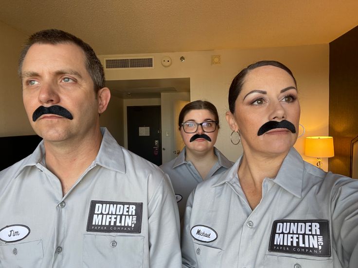 three people with fake moustaches on their faces are standing in front of a mirror