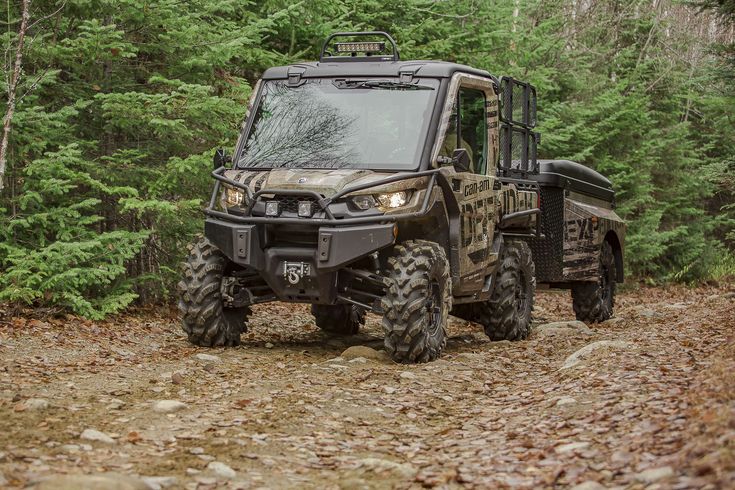 an atv driving down a dirt road in the woods