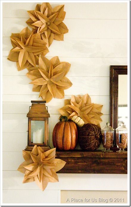 paper flowers and pumpkins on a mantle in front of a mirror with a lantern