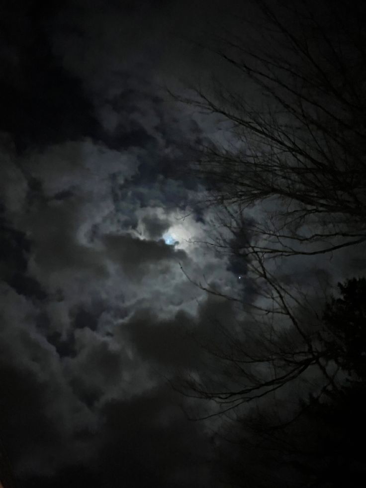 the moon shines brightly through dark clouds