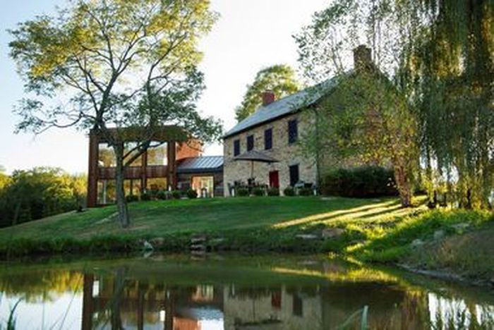 a large house sitting on top of a lush green hillside next to a lake in front of it