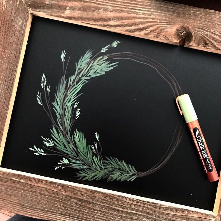 a chalkboard with some green leaves on it and a marker in front of it