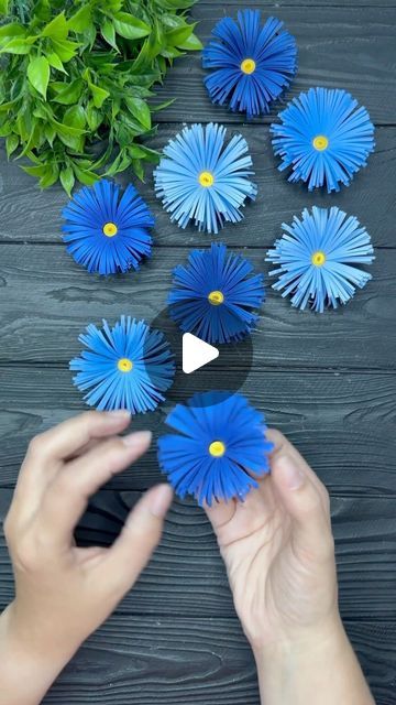 someone is holding blue paper flowers in their hands