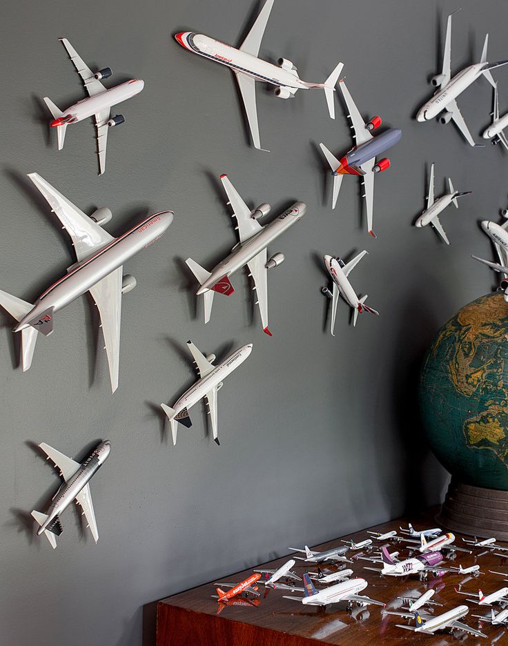 a bunch of airplanes are hanging on the wall next to a table with a globe