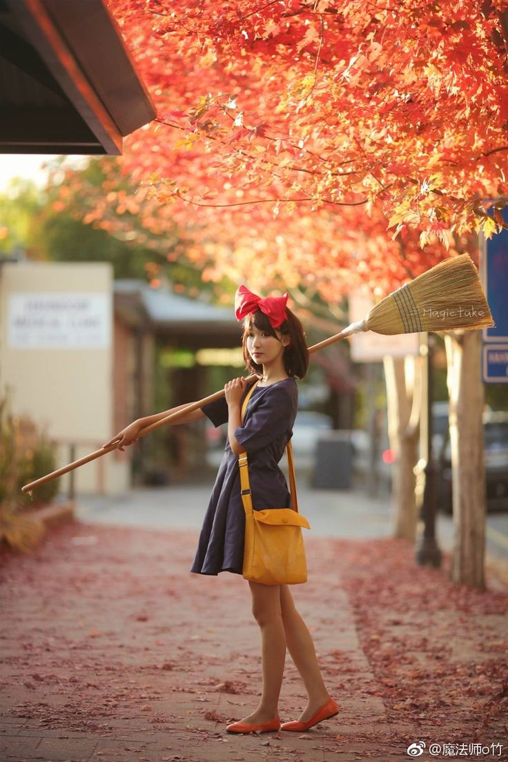 a woman is talking on her cell phone while holding a broom in one hand and wearing a red bandana