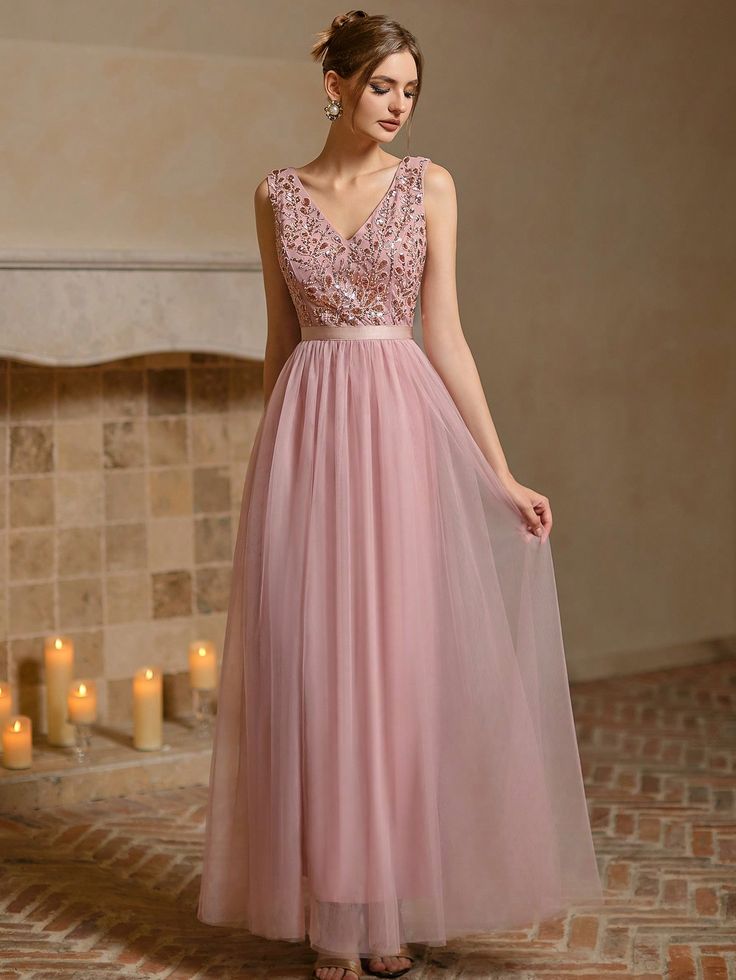 a woman in a long pink dress standing next to candles and looking at the camera