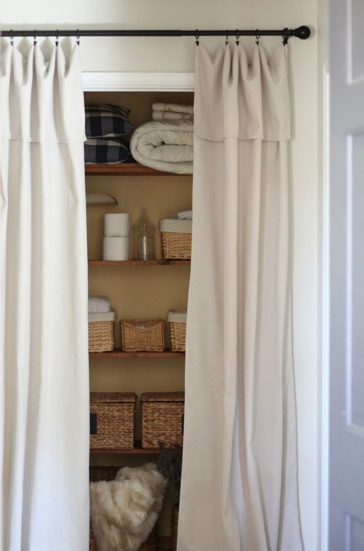 an open closet with white curtains and baskets