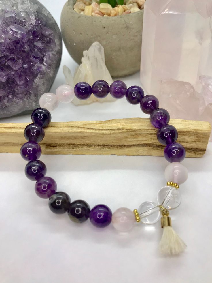 "Call in the life you want, live as you desire, create your blissful reality! Three of the most powerful stones are used in our Manifest bracelet: rose quartz, clear quartz, and amethyst. Amethyst, the \"all-healer,\" is extremely effective in combating dis-ease within the body and mind. It protects against any ill-wishes and negative energy by absorbing it and then transforms it into positive, loving energy before sending it back into the universe. Rose quartz, the stone of love and nurturing, Spiritual Rose Quartz Gemstone Beaded Bracelets, Spiritual Rose Quartz Beaded Bracelets With Gemstones, Rose Quartz Crystal Bracelet For Meditation, Rose Quartz Round Crystal Bracelet For Meditation, Round Rose Quartz Crystal Bracelet For Relaxation, Spiritual Rose Quartz Bracelet With Gemstone Beads, Spiritual Rose Quartz Beaded Bracelets With Natural Stones, Rose Quartz Gemstone Bracelet For Meditation, Rose Quartz Gemstone Beads Bracelet For Meditation