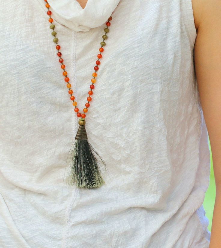 "Complete a boho-chic look with this statement necklace. A beautiful bead necklace made stunning by Carnelian stones and an olive green tassel. Bring these warm and cool colors to your ensembles with this mala necklace. Product Details: ---------------------- Materials: *carnelian stone Measurements: Length of the tassel: 3 \"/ 7.6 cm. Chain length 30\" / 76cm Why purchase this Mala Necklace? Carnelian is known as the \"Stone of Joy\" ✅ The necklace are expertly handmade with craftsmanship and h Bohemian Orange Jewelry For Meditation, Bohemian Orange Hand-strung Necklace, Bohemian Crystal Necklaces With Faceted Beads For Beach, Bohemian Crystal Necklace With Faceted Beads For Beach, Bohemian Hand-strung Orange Beads, Hand-strung Orange Bohemian Beads, Bohemian Orange Long Necklace, Festival Agate Beaded Necklaces, Multicolor Carnelian Bohemian Necklaces