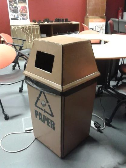 a brown trash can sitting on top of a floor next to chairs and desks