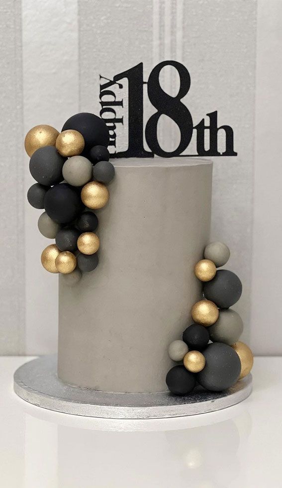 a birthday cake decorated with black, white and gold decorations