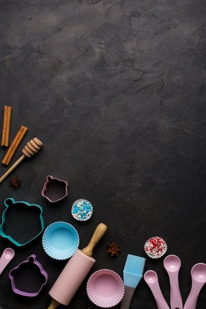 various baking utensils and cookie cutters laid out on a black surface with space for text